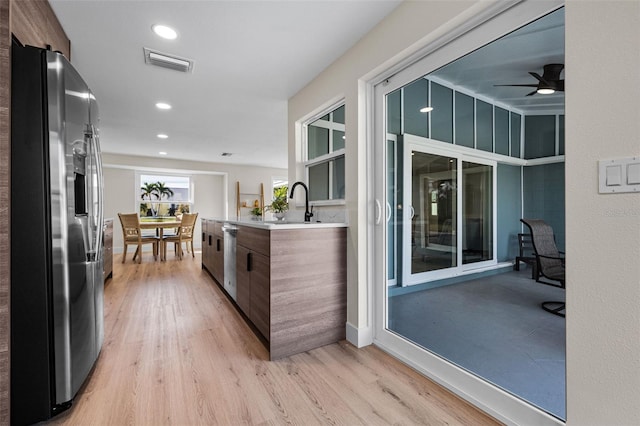 kitchen featuring ceiling fan, appliances with stainless steel finishes, sink, and light hardwood / wood-style floors