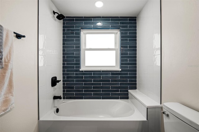 bathroom with tiled shower / bath combo and toilet