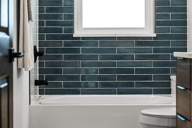 bathroom with tiled shower / bath combo and toilet