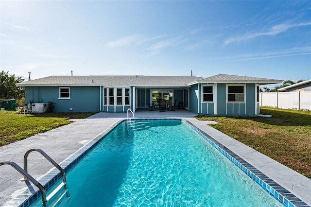 back of property featuring a fenced in pool, a patio area, and a lawn