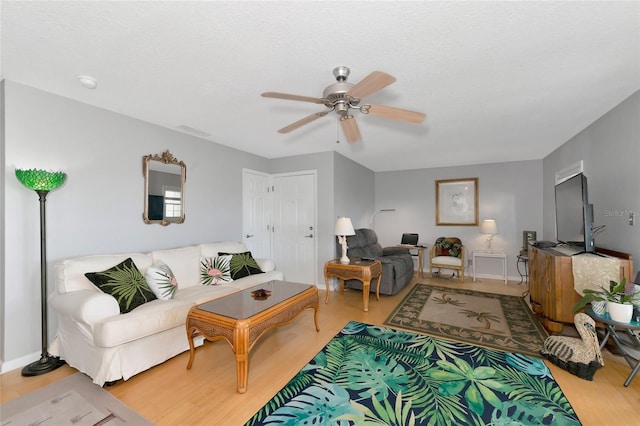 living room featuring a textured ceiling, ceiling fan, and light hardwood / wood-style flooring