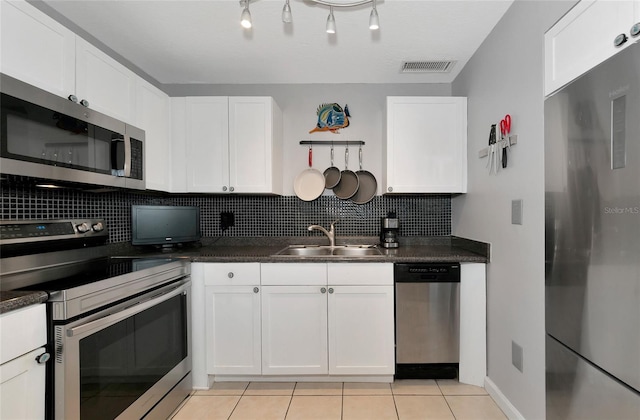 kitchen featuring light tile patterned flooring, sink, tasteful backsplash, stainless steel appliances, and white cabinets