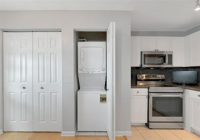 kitchen featuring backsplash, stacked washer and clothes dryer, white cabinets, and appliances with stainless steel finishes