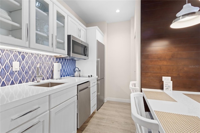 kitchen featuring sink, white cabinetry, pendant lighting, stainless steel appliances, and decorative backsplash