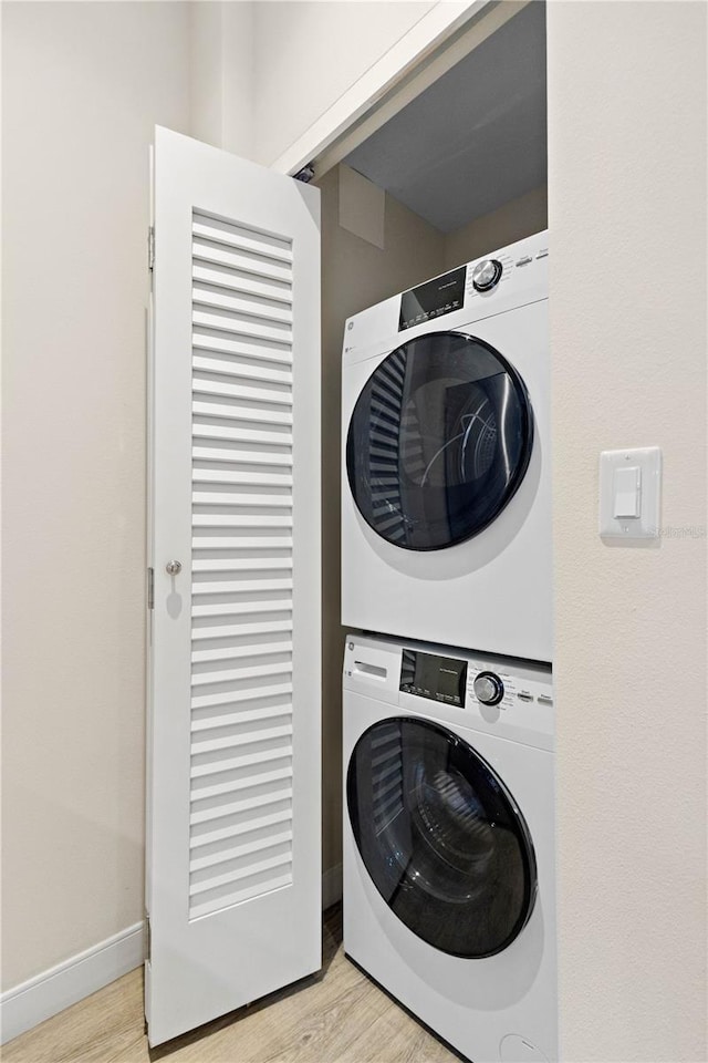 laundry area featuring stacked washer and clothes dryer and light hardwood / wood-style floors