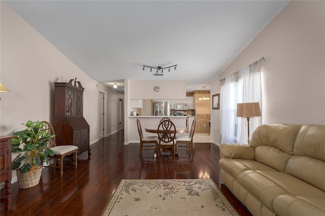 living room featuring track lighting, lofted ceiling, and dark hardwood / wood-style flooring