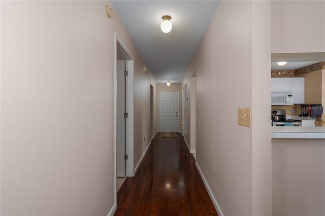 hallway with dark hardwood / wood-style floors and a textured ceiling