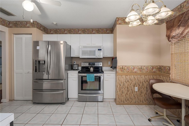 kitchen with a textured ceiling, pendant lighting, ceiling fan, stainless steel appliances, and white cabinets