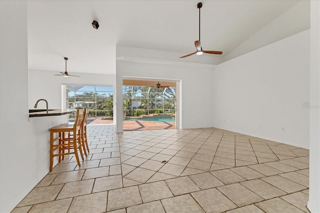 empty room featuring ceiling fan, vaulted ceiling, and light tile patterned floors