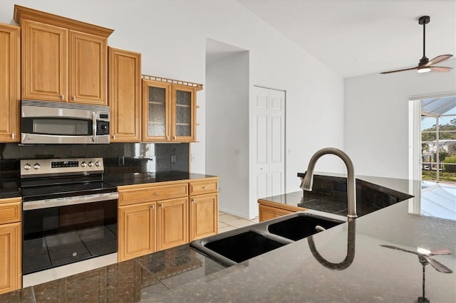 kitchen featuring appliances with stainless steel finishes, backsplash, vaulted ceiling, a ceiling fan, and glass insert cabinets