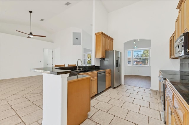 kitchen with stainless steel appliances, light tile patterned flooring, a sink, a peninsula, and high vaulted ceiling