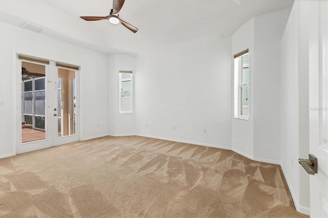 carpeted empty room featuring a ceiling fan, healthy amount of natural light, baseboards, and french doors