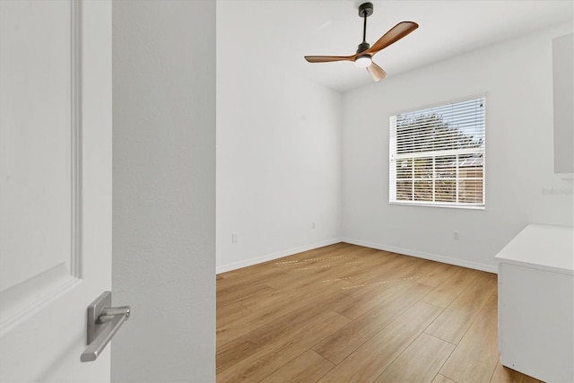 spare room featuring light wood-type flooring, ceiling fan, and baseboards