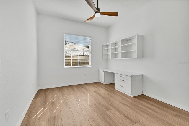 unfurnished office with light wood-type flooring, ceiling fan, baseboards, and built in study area