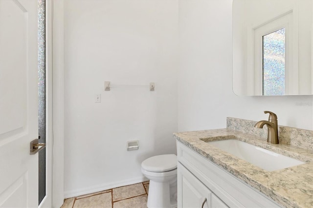 bathroom featuring vanity, toilet, baseboards, and tile patterned flooring