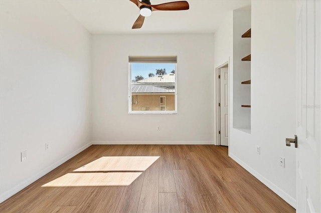 unfurnished room featuring wood finished floors, a ceiling fan, and baseboards