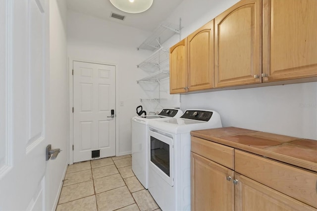 laundry area featuring washer and clothes dryer, light tile patterned flooring, and cabinet space