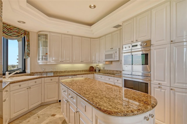 kitchen featuring double oven, sink, a center island, black electric stovetop, and light stone counters