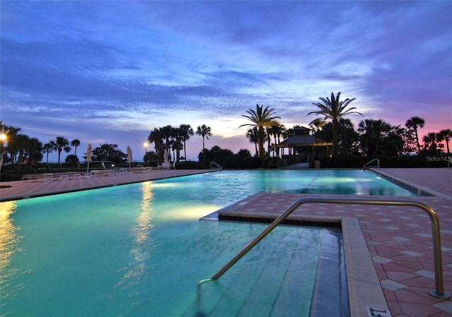 pool at dusk featuring a patio area