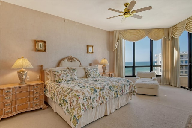 carpeted bedroom featuring ceiling fan and a water view