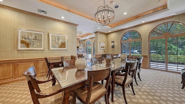 carpeted dining room featuring crown molding, a tray ceiling, and a chandelier