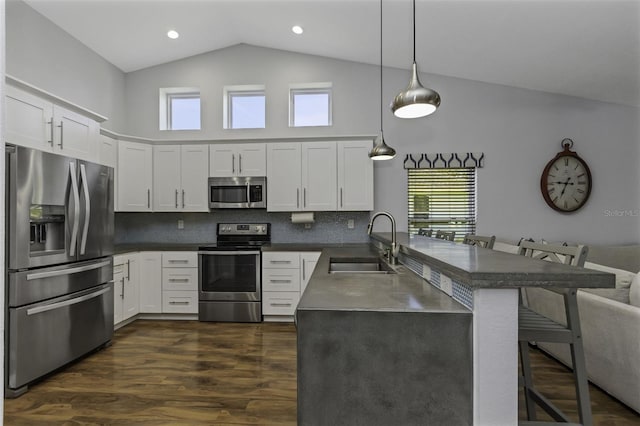 kitchen featuring sink, hanging light fixtures, stainless steel appliances, a kitchen breakfast bar, and kitchen peninsula