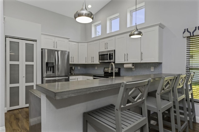 kitchen with white cabinetry, appliances with stainless steel finishes, kitchen peninsula, and a breakfast bar area