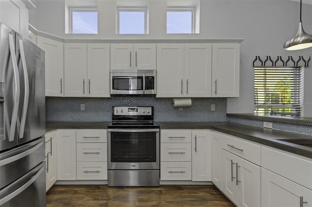 kitchen with hanging light fixtures, backsplash, white cabinets, and appliances with stainless steel finishes