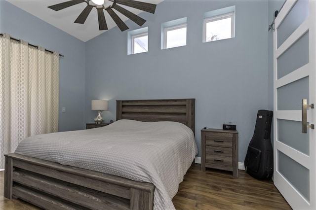 bedroom featuring dark hardwood / wood-style floors, ceiling fan, and a barn door