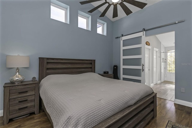 bedroom with a barn door, dark hardwood / wood-style floors, lofted ceiling, and ceiling fan