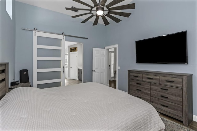 bedroom featuring ensuite bathroom, a barn door, hardwood / wood-style floors, and ceiling fan