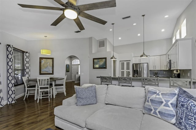 living room featuring dark hardwood / wood-style floors, ceiling fan, and a high ceiling