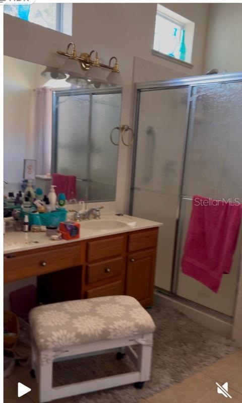 bathroom with tile patterned flooring, vanity, and a shower with shower door