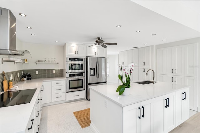 kitchen featuring white cabinetry, wall chimney range hood, a center island, and appliances with stainless steel finishes