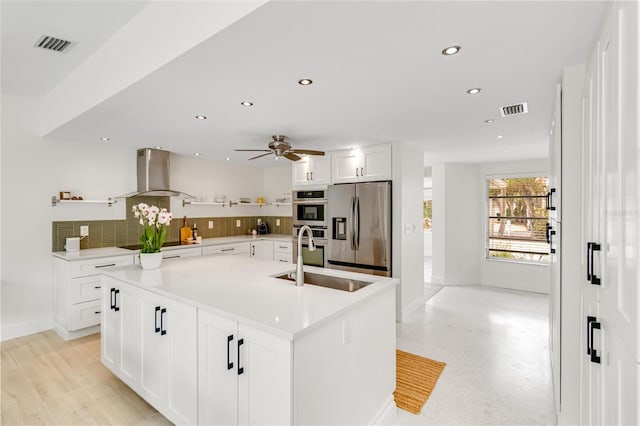 kitchen featuring sink, stainless steel appliances, extractor fan, white cabinets, and a center island with sink