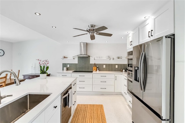 kitchen with sink, white cabinets, backsplash, stainless steel appliances, and wall chimney range hood