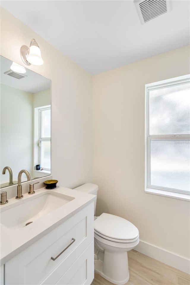 bathroom with vanity, toilet, and hardwood / wood-style floors