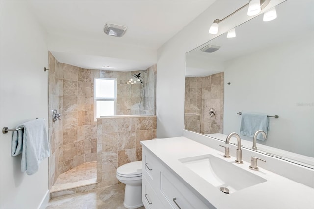 bathroom with vanity, toilet, and a tile shower