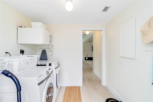 washroom with cabinets, washer and clothes dryer, and light hardwood / wood-style flooring