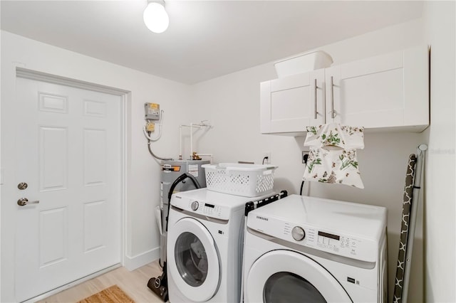 clothes washing area with cabinets, washing machine and dryer, and light hardwood / wood-style flooring