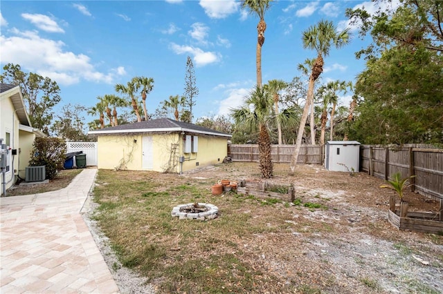 rear view of property featuring a shed, central AC, and an outdoor fire pit