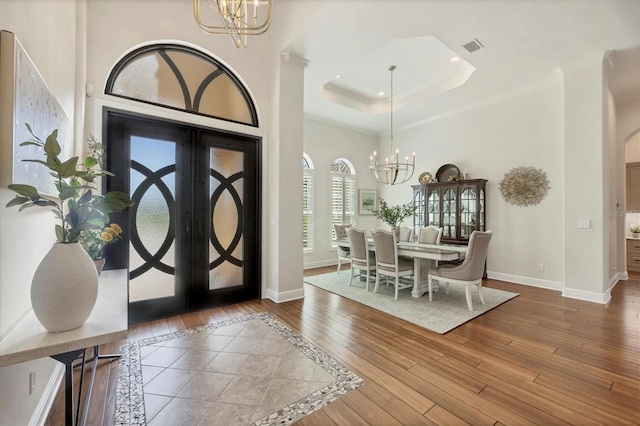 foyer with wood-type flooring, french doors, and an inviting chandelier