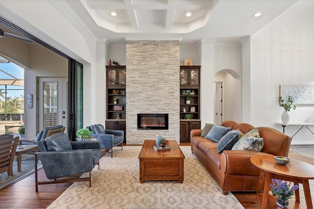 living area featuring arched walkways, ornamental molding, a fireplace, and hardwood / wood-style flooring