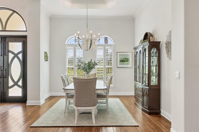 dining area with a chandelier, baseboards, crown molding, and hardwood / wood-style floors