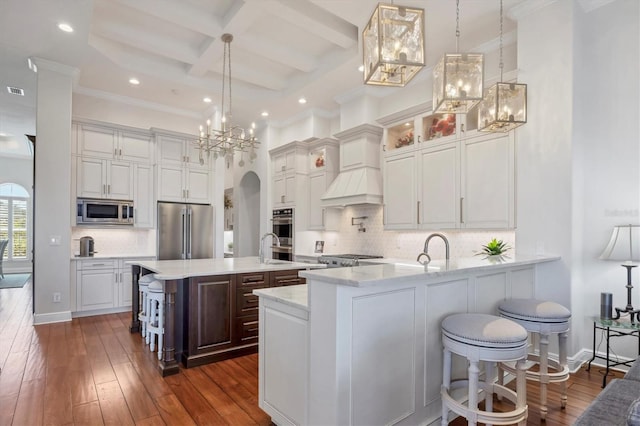 kitchen with arched walkways, coffered ceiling, dark wood-type flooring, stainless steel appliances, and white cabinetry