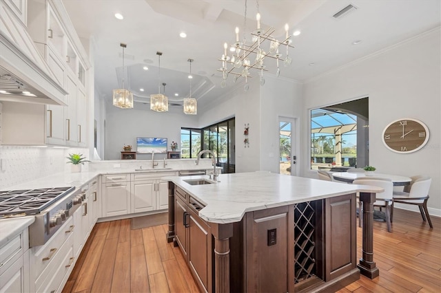 kitchen with visible vents, light wood-style flooring, premium range hood, stainless steel gas stovetop, and a sink