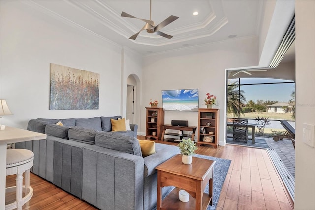 living room featuring arched walkways, ceiling fan, wood finished floors, a high ceiling, and crown molding