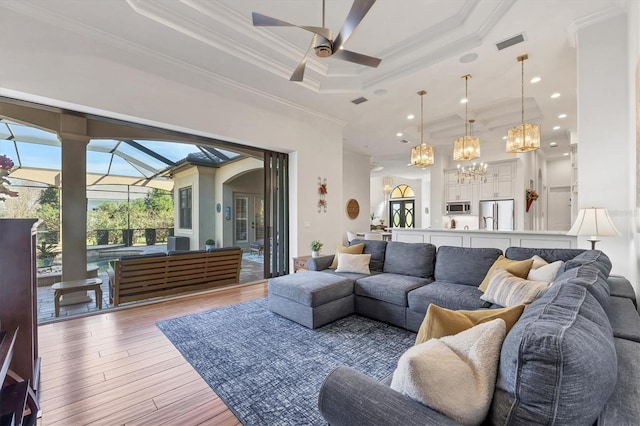 living room with crown molding, visible vents, a raised ceiling, and wood finished floors