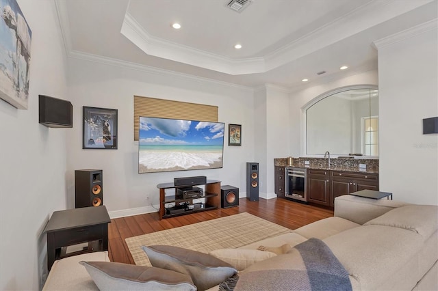 living room with dark wood-style floors, crown molding, a raised ceiling, visible vents, and beverage cooler