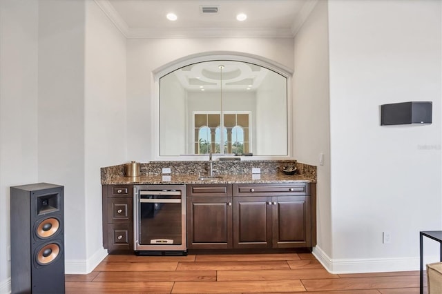 bar with ornamental molding, wine cooler, and light wood-style floors